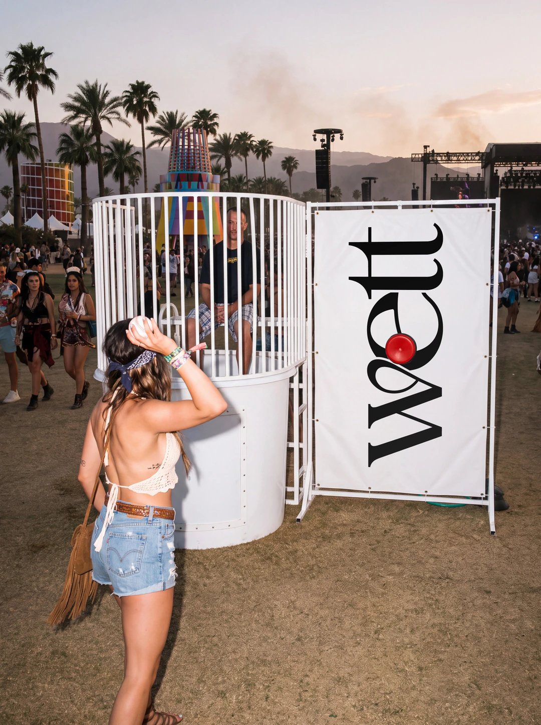 A festival-goer at a Wett dunk tank beside a Wett banner.