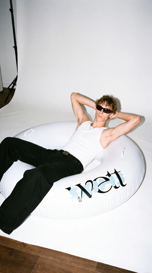 A model lying on a white Wett ring in black trousers.