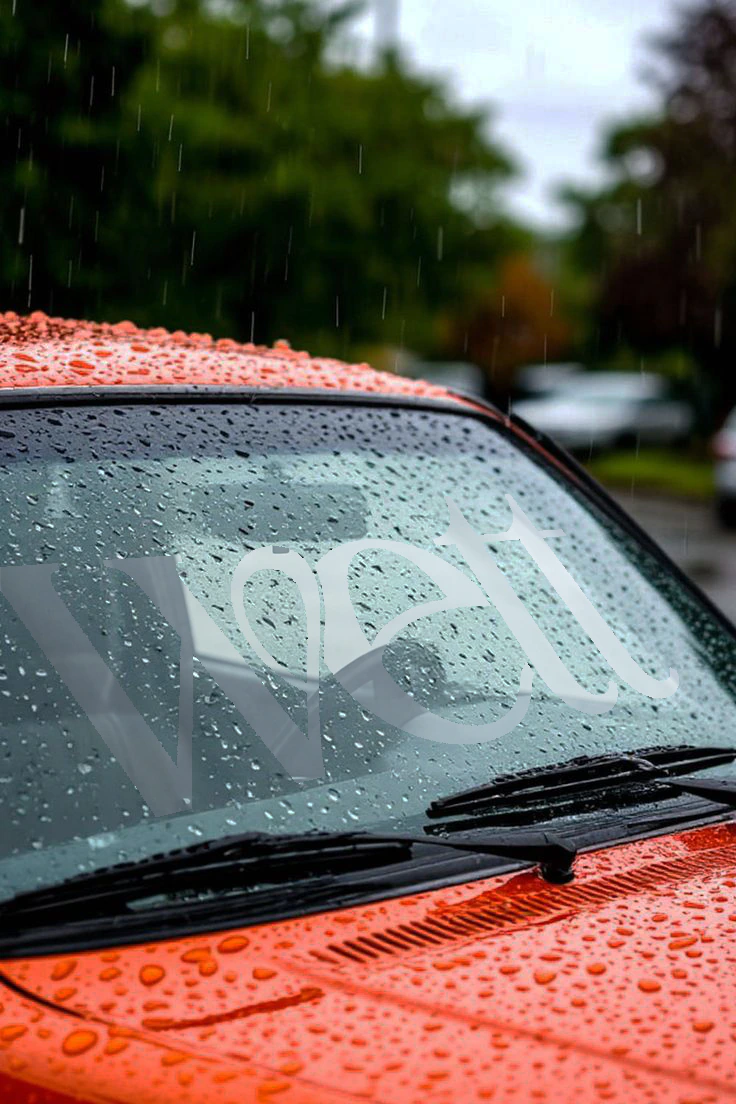 Close-up of a rain-covered car windscreen, the Wett logo left dry in the spray.