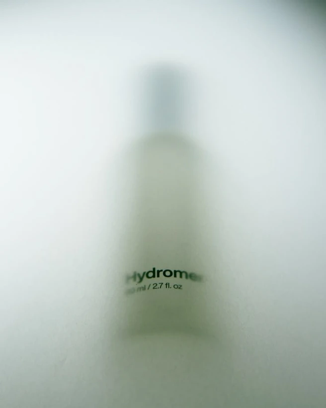 A frosted skincare bottle, softly out of focus.