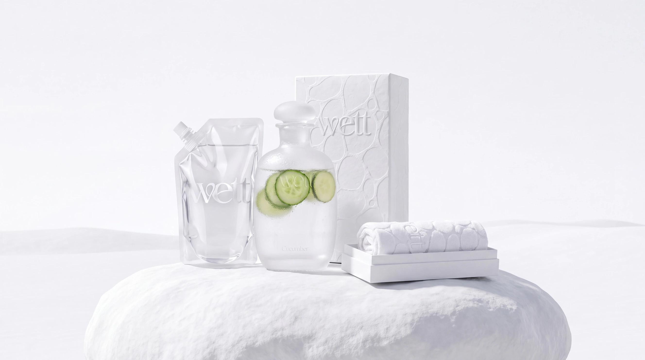 The white Wett box, bottle, refill pouch and towel arranged on a white rock.