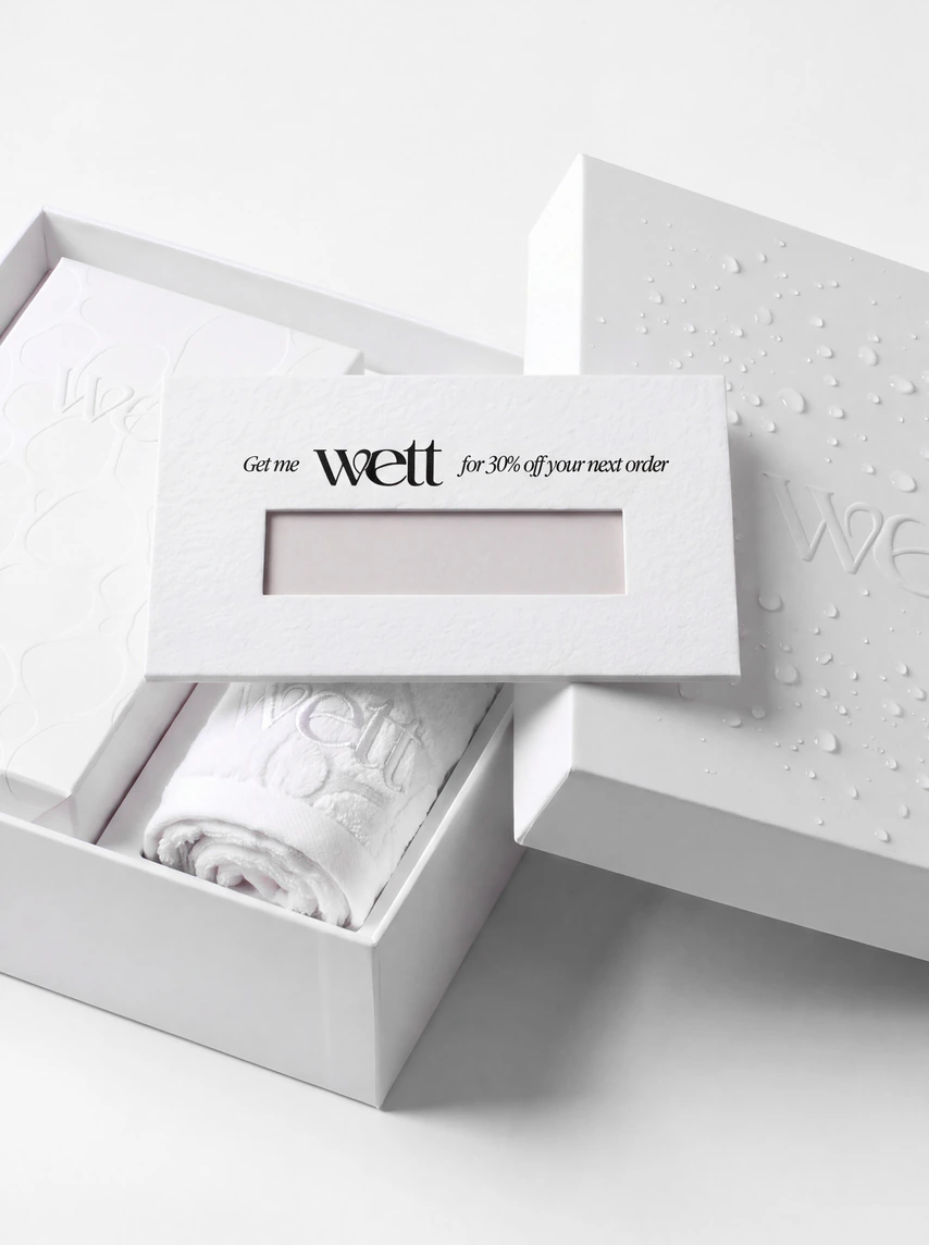 An open Wett box with the discount card on top of a folded towel.
